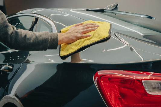 Hand wiping a glossy car panel with microfiber before paint protection